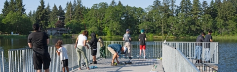 Eight Service event attendees fishing from a lake dock. 