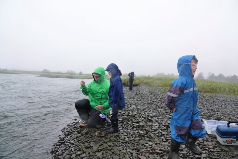 kids learning to fish on a river bank