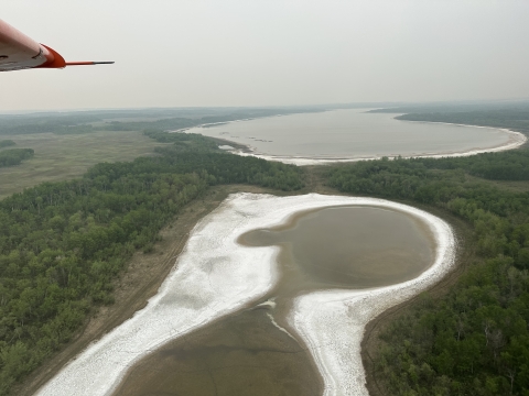 view of an airplane wing with smoke in the landscape