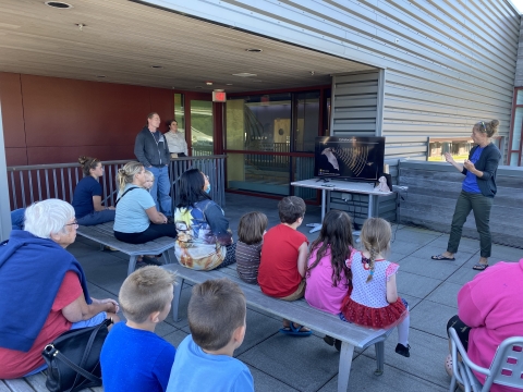 a woman presents about bats to a group of children and adults