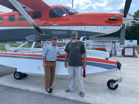 two people standing in front of an airplane