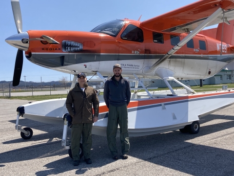 two people standing in front of an airplane