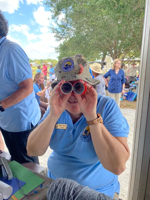 Volunteer looks through carboard binoculars at camera.