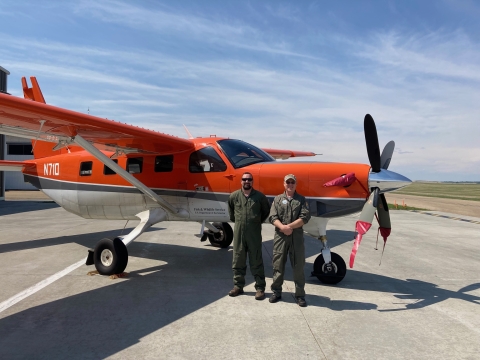 two people standing in front of an airplane