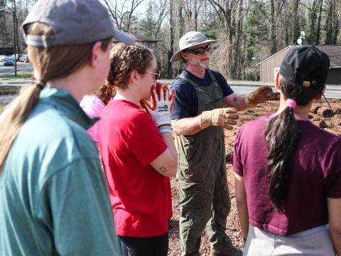 A group of people standing together with one person speaking while others listen.