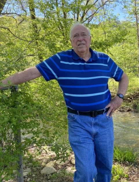 A man standing alongside a creek.