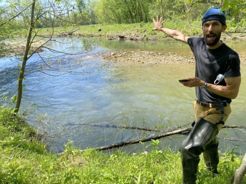 A man gestures towards a creek.