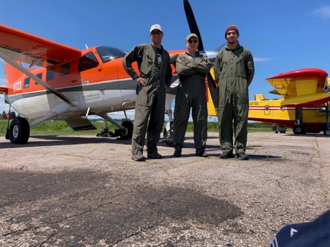 three people standing in front of an airplane 