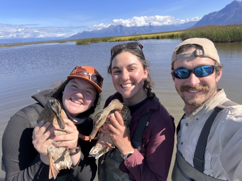 three people smiling, 2 are holding ducks