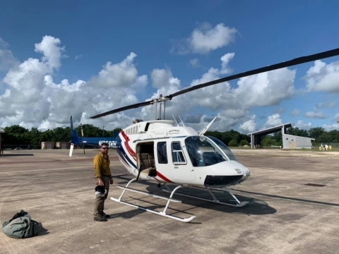 USFWS Firefighter Ron Deroche stands next to a helicopter on the tarmac