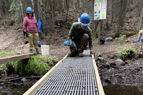 Two people in hard hats at a small footbridge 