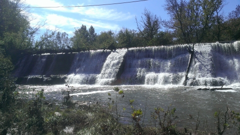 White waters pour over a large concrete dam.