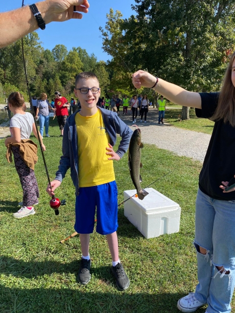 Boy holding fishing road looking at fish caught