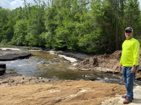 A man standing alongside a creek.