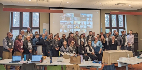 A group of people at a conference pose for a group photo. 