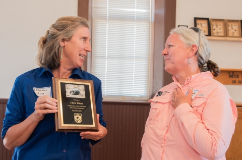 One person presents a plaque to another person.