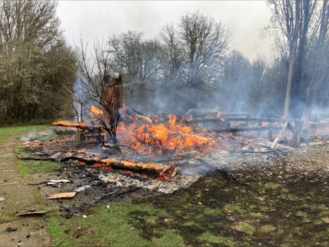 A fire smolders in the ruins of an old house.