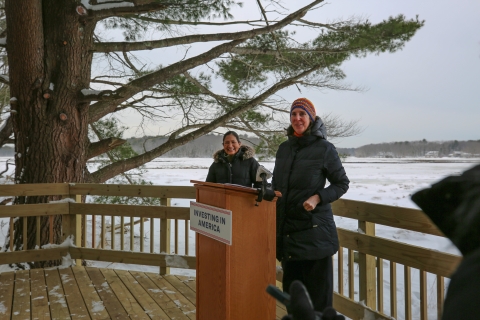 Two women stand on a deck overlooking a snowy landscape