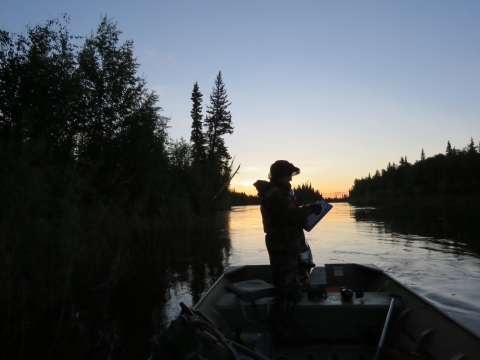 Silhouette of a person in a boat on a river at sunrise