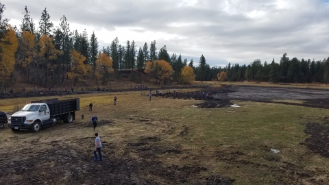 A group of middle school students plants trees as part of a habitat restoration project