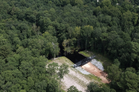 A metal structure dams a ditch and prevents water from flowing out. 