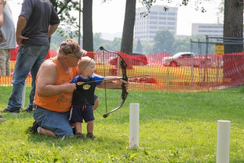 Man teaches boy how to use bow and arrow