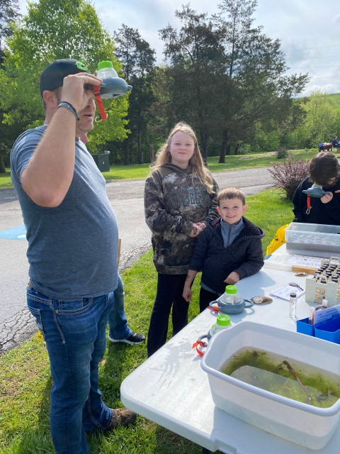 people looking at macroinvertebrates through a magnifier