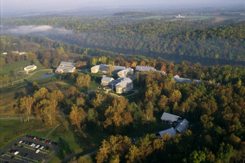 aerial image of campus with buildings, trees, and a river running in background