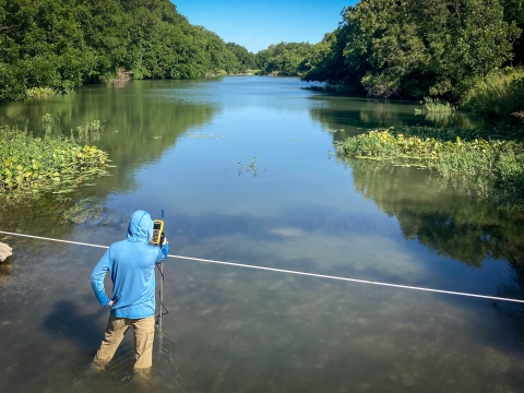 A researcher takes measurements at a mussel research site on the San Saba River