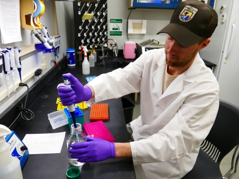 Man using pipette in lab.