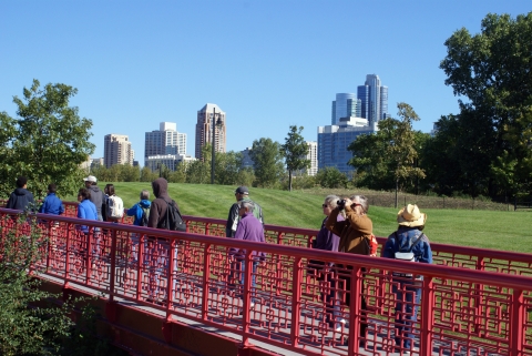 People walking across a bridge with the city of Chicago in the background