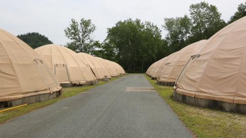 A paved road lined by circular, canvas-covered fish rearing tanks.