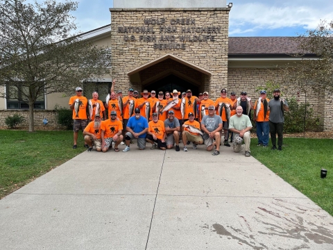 Group of people in orange shirts holding fish