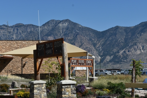 Signs at the Bear River Migratory Bird Refuge's Nature Play Area and Outdoor Classroom. "Welcome. Tsaa yu saikki. Bienvenidos." and "Play. Discover. Learn" signs in front of a mountain background