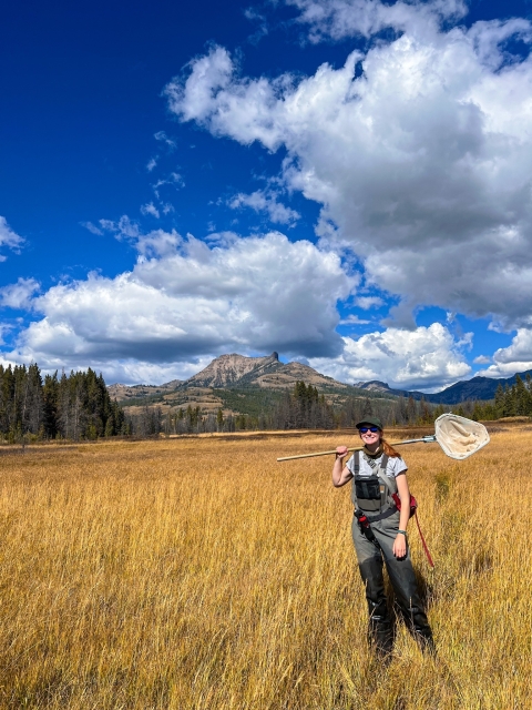 Woman standing in field holding a dipnet