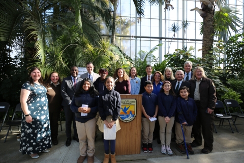 Group photo of adults and youth smiling. A U.S. Fish and Wildlife Service logo can be seen on a podium in the center of the photo