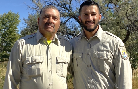 Two men in uniform smiling in an outdoor setting