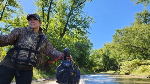 Madie McFarland driving a boat in a backwater slough along the Mississippi River while monitoring a Ducks Unlimited conservation easement. 