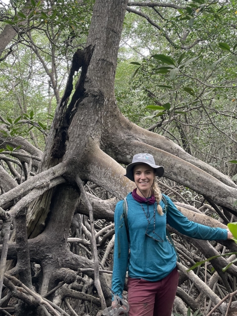 a woman in front of a mangrove tree