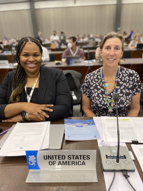 two women sitting at table with sign that reads United States of America