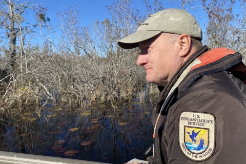 A man, his ballcap, on a boat.