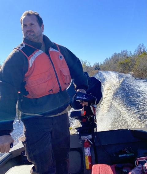 A man steers a boat through the swamp.