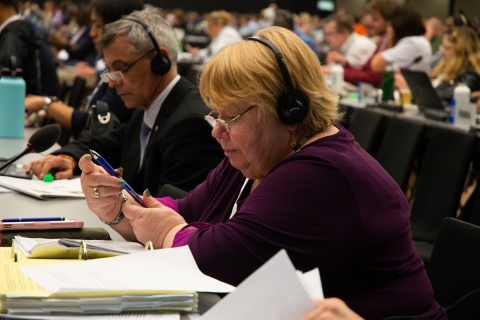 woman in purple shirt and headphones sitting in auditorium