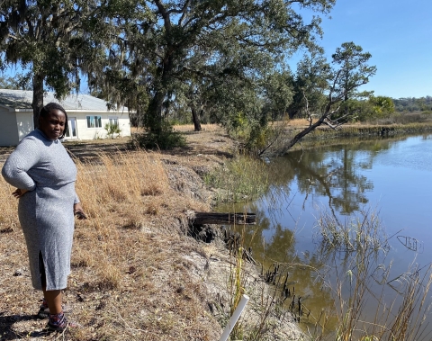 A woman overlooks an eroded shoreline.