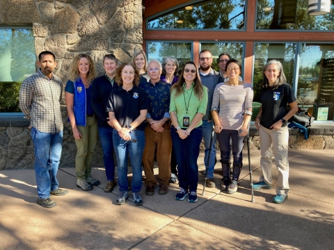 12 people standing outside a building smiling for the camera, some with USFWS logo wear.