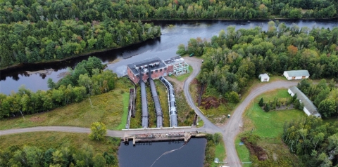 Large building by river with trees seen from above.