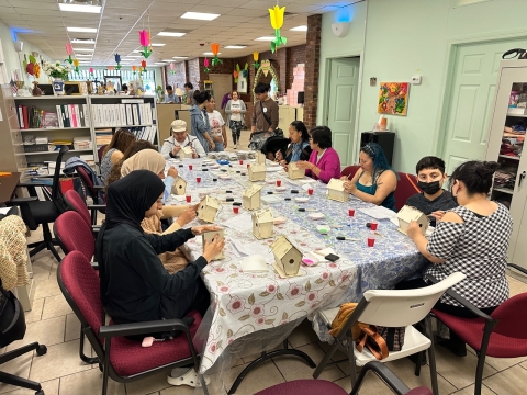 several people sit around a table building birdhouses