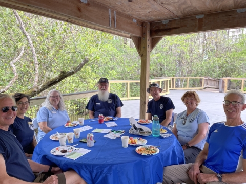 A picture of seven volunteers sitting around a blue table. 