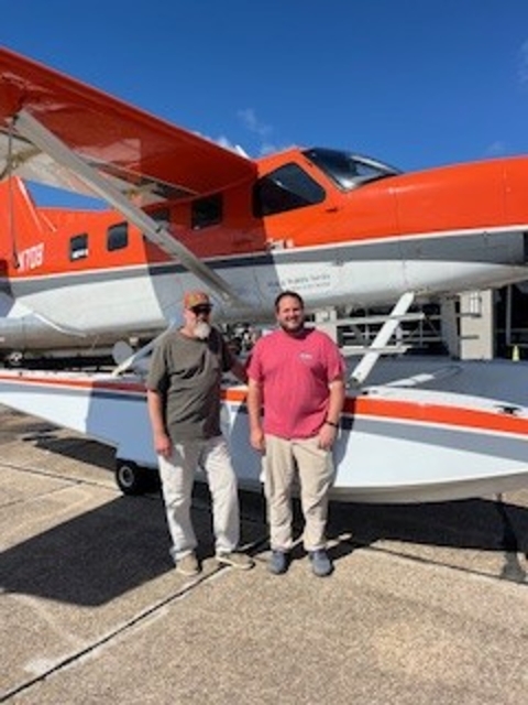 two people standing in front of an airplane