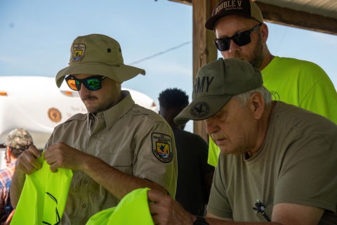 Two people, Service member and Veteran, sort tee-shirts 